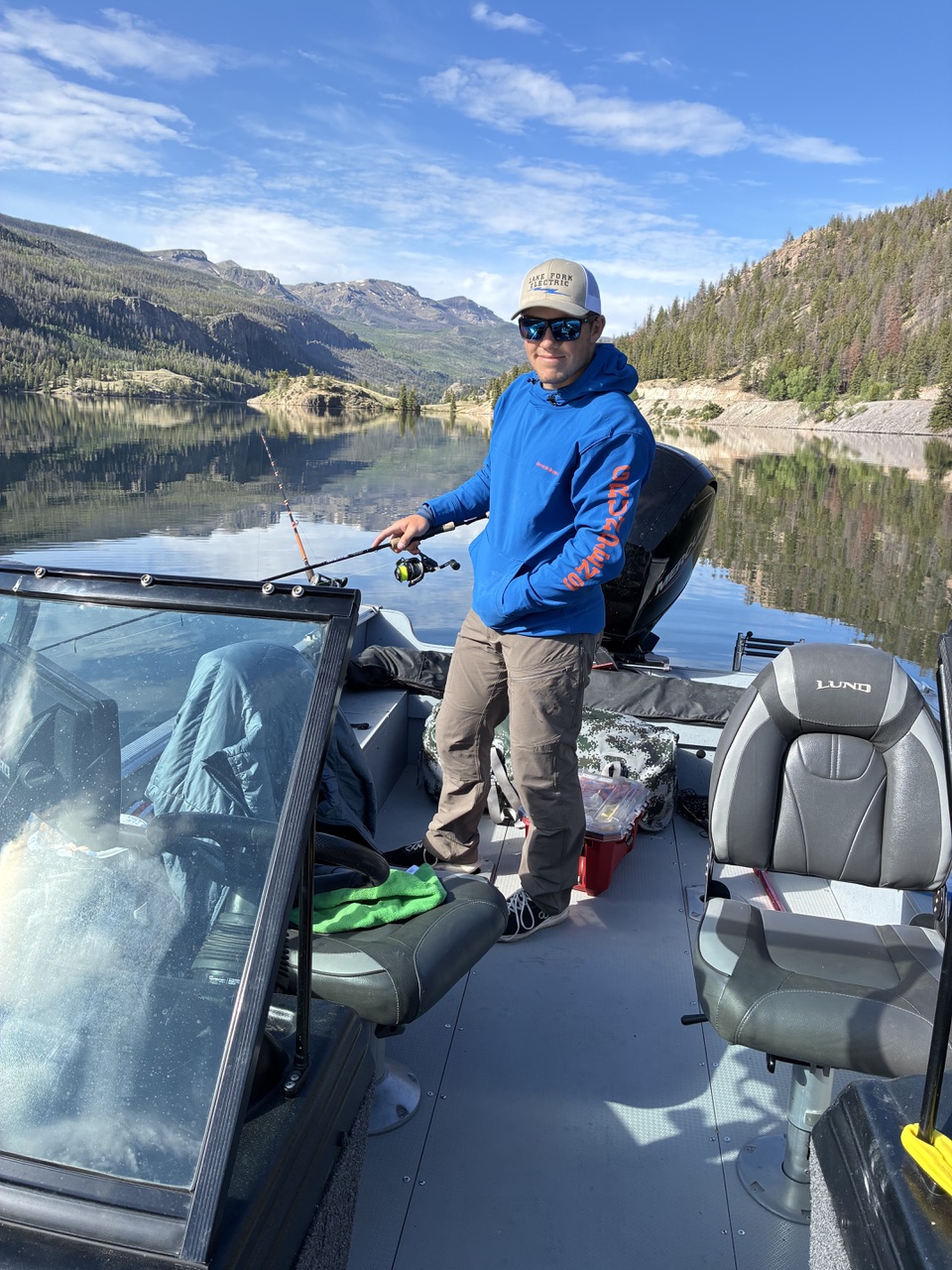 Jack Doughty fishing on a mountain lake in Colorado wearing a LakeFork Electric hoodie